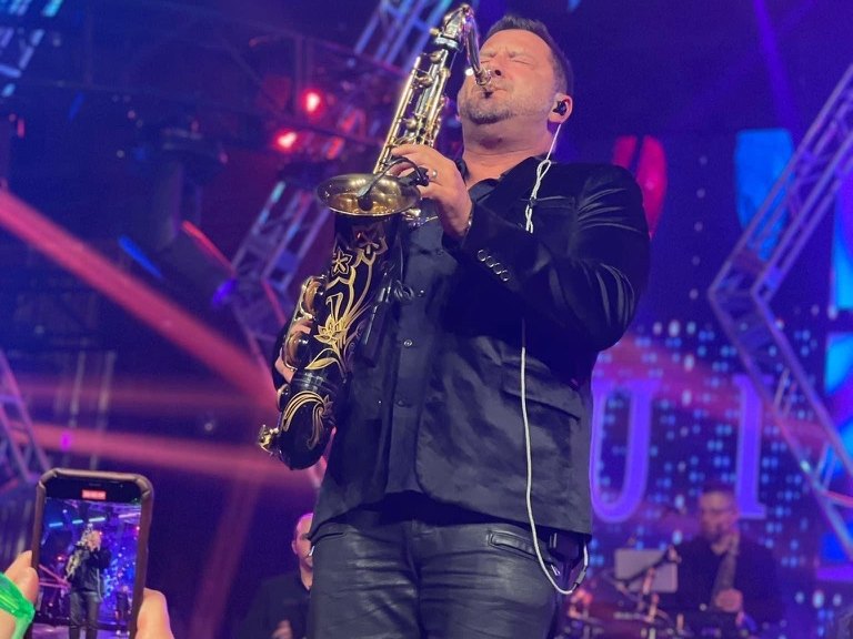 Guests filming a Sugar Shaker saxophone solo on their phones at a corporate party