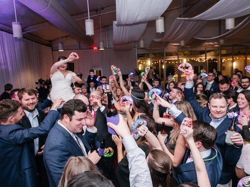 A bride celebrating above the crowd during a Sugar Shaker reception