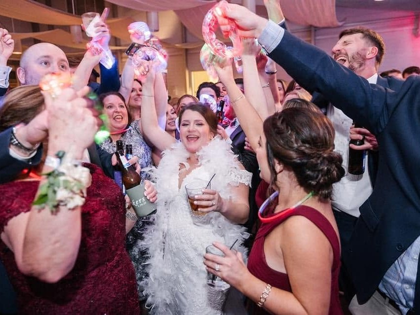A bride surrounded by cheering guests on a full wedding dance floor