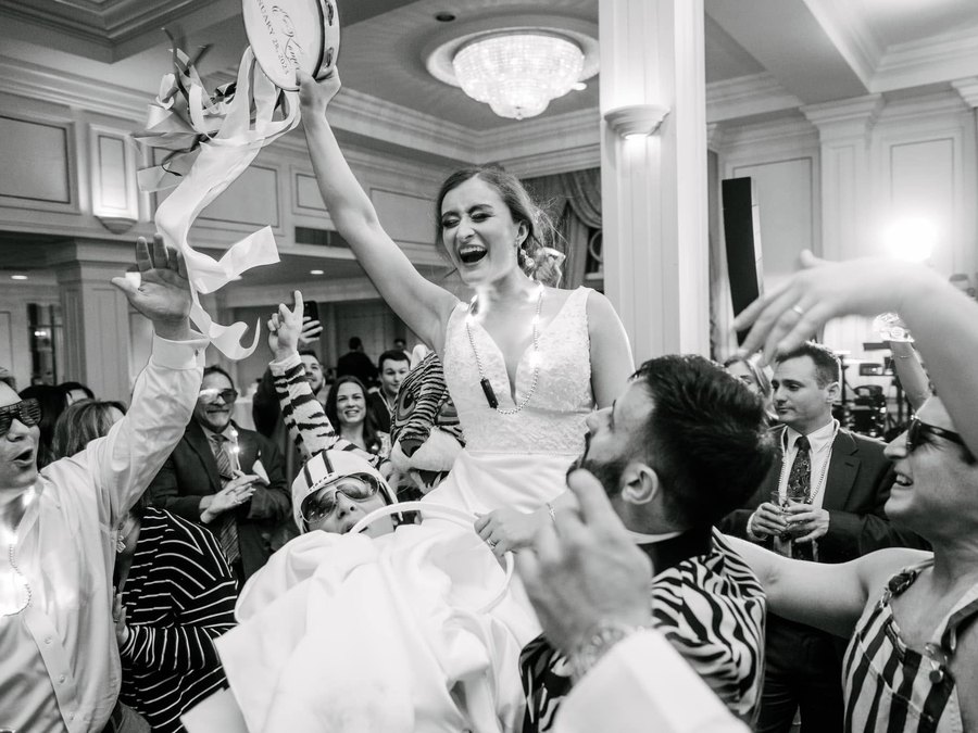 A bride lifted above the crowd with a tambourine at her New Orleans wedding reception