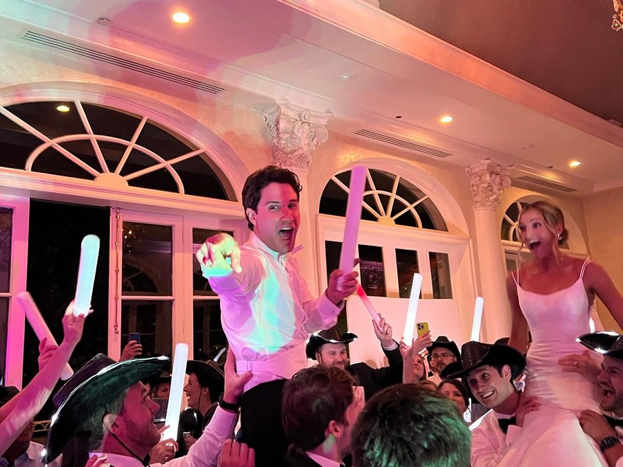 A bride and groom raised above a glow-lit dance floor at their wedding