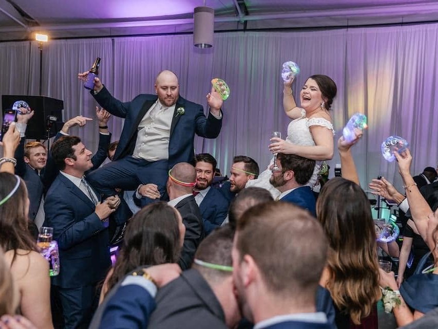 A bride and groom lifted on chairs by their guests during the reception