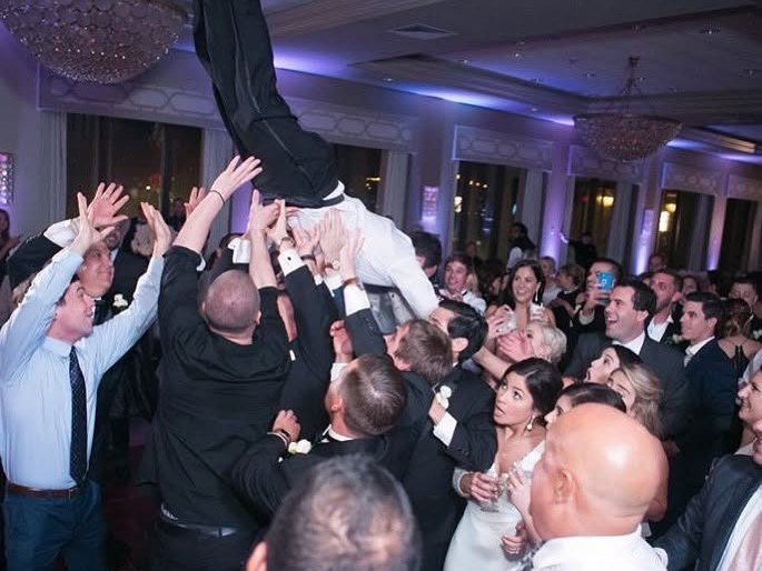 Wedding guests throwing the groom into the air on the dance floor